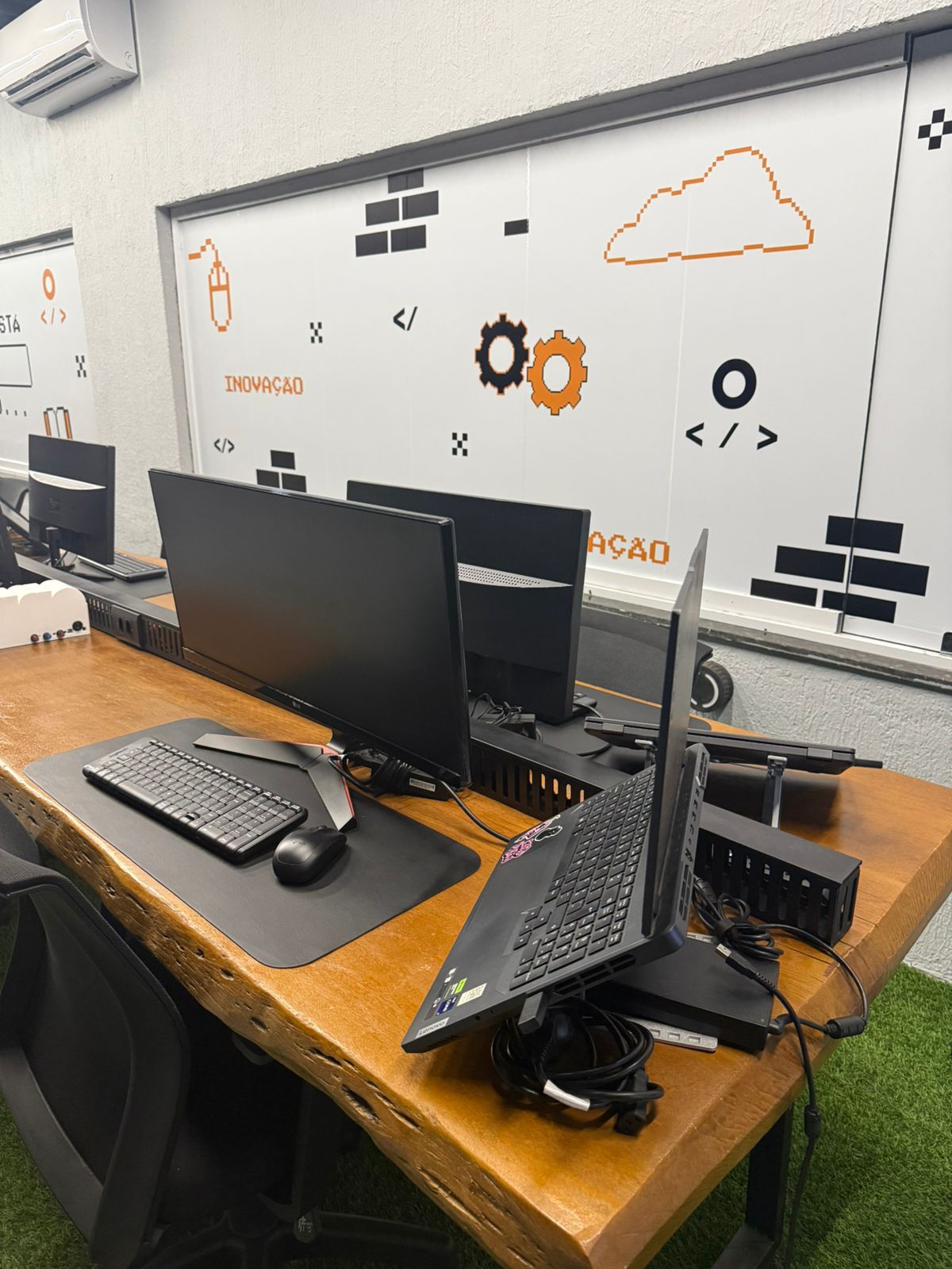 Bancada de trabalho com monitores e identidade visual do CodeLAB
